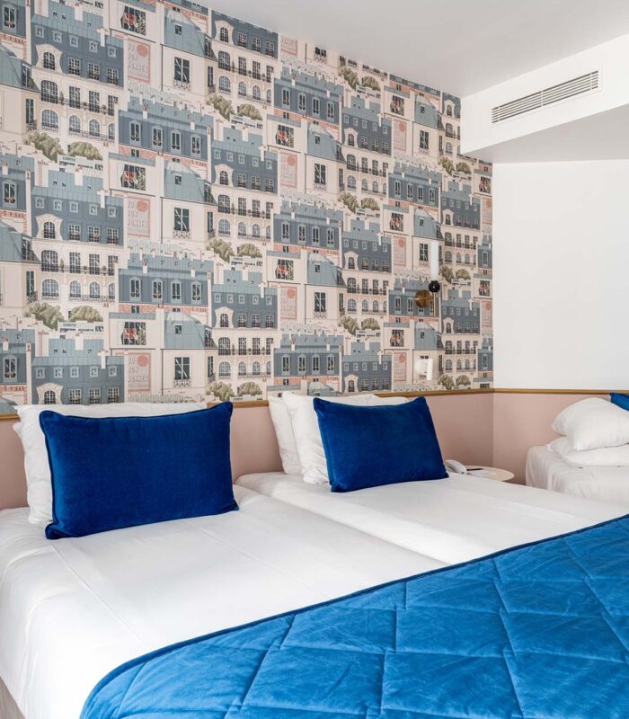 Chambre triple avec deux lits et un papier peint représentant des bâtiments à l’Hôtel Acadia