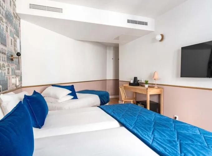 Chambre triple avec deux lits et une télévision à écran plat à l’Hôtel Acadia