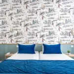 Chambre Twin avec lits et oreillers bleus devant un mur orné de dessins à l’hôtel Acadia