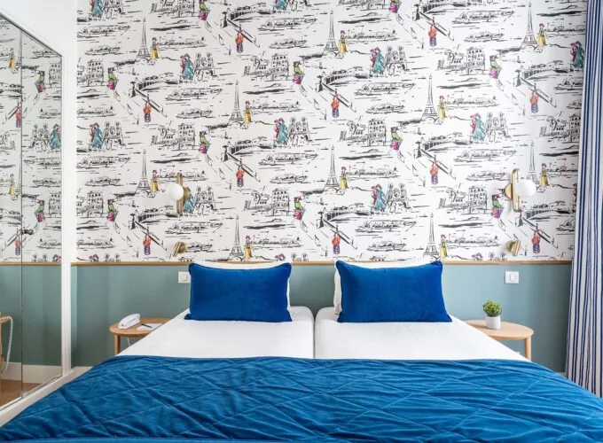 Chambre Twin avec lits et oreillers bleus devant un mur orné de dessins à l’hôtel Acadia