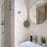 Chambre Twin avec salle de bain comprenant un lavabo et un miroir rond à l’hôtel Acadia