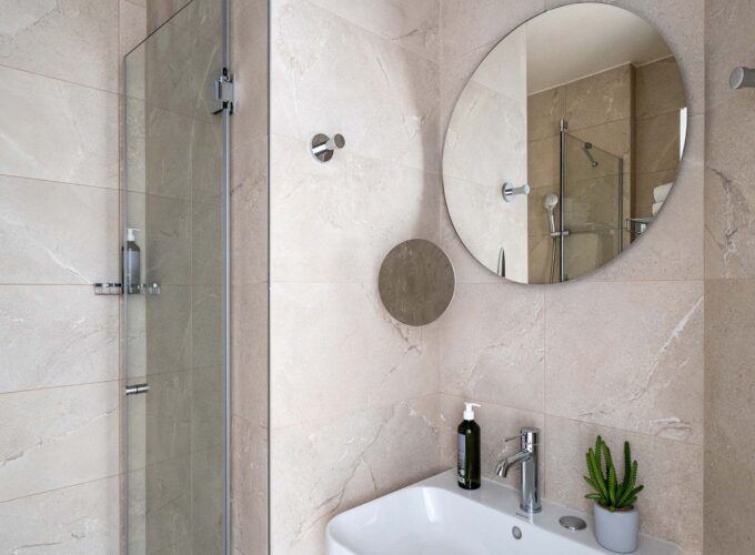 Chambre Twin avec salle de bain comprenant un lavabo et un miroir rond à l’hôtel Acadia