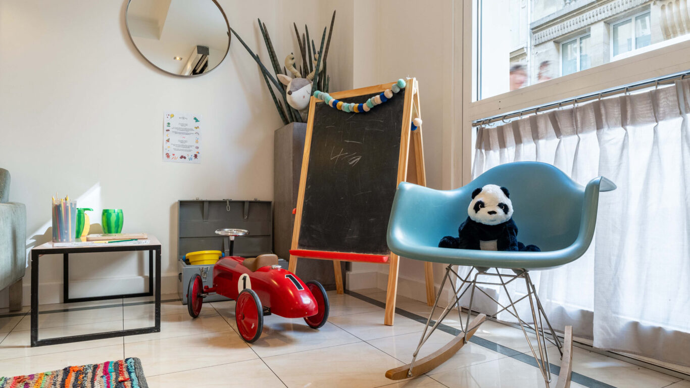 Hall d'accueil de l'hôtel 3 étoiles Acadia à Paris avec des couleurs élégantes et un espace pour enfants.