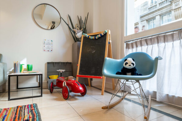 Hall d'accueil de l'hôtel 3 étoiles Acadia à Paris avec des couleurs élégantes et un espace pour enfants.