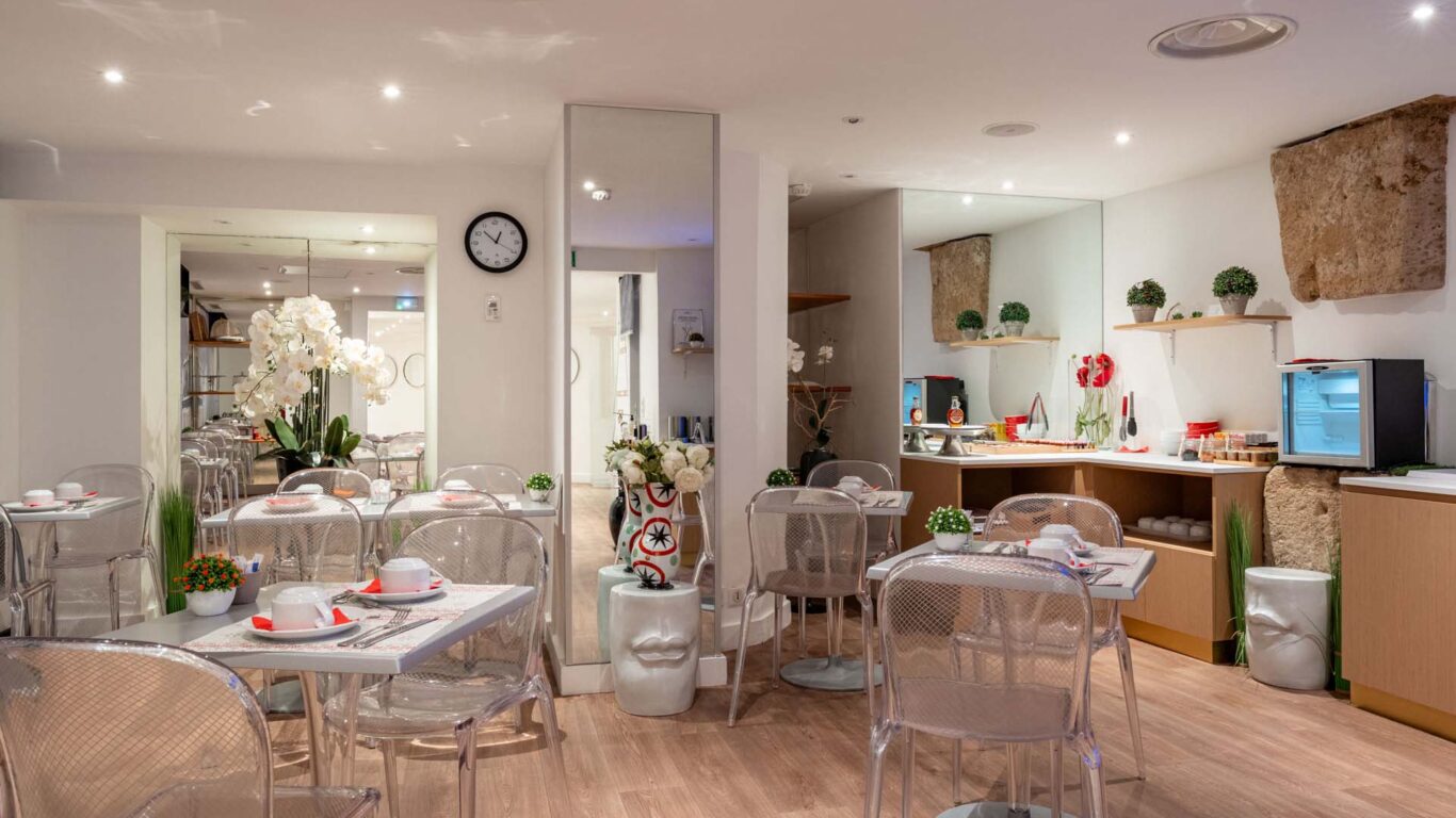 Salle de petit-déjeuner de l'hôtel Acadia à Paris avec buffet varié et ambiance chaleureuse et accueillante.