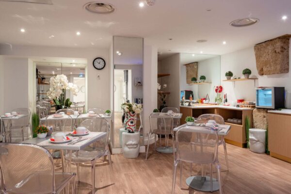 Salle de petit-déjeuner de l'hôtel Acadia à Paris avec buffet varié et ambiance chaleureuse et accueillante.