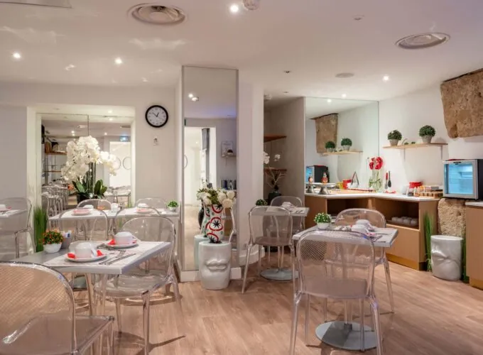Salle de petit-déjeuner de l'hôtel Acadia à Paris avec buffet varié et ambiance chaleureuse et accueillante.