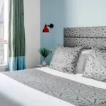 Vue du lit de la chambre double à l’hôtel Astoria, Paris