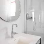 Salle de bain de la Chambre Familiale avec un lavabo et un miroir rond à l’hôtel Astoria