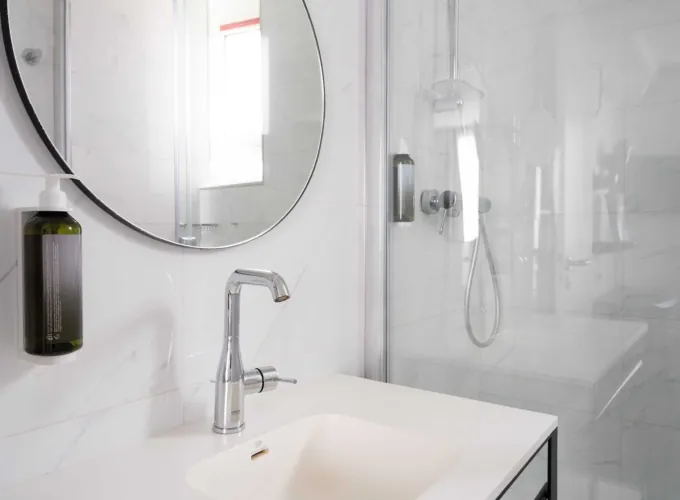 Salle de bain de la Chambre Familiale avec un lavabo et un miroir rond à l’hôtel Astoria