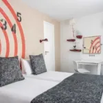 Chambre Familiale avec deux lits et un mur décoré de chiffres à l’hôtel Astoria