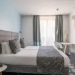 Chambre Familiale Supérieure avec deux lits et un bureau à l’hôtel Astoria