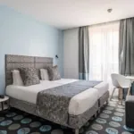 Chambre Familiale Supérieure avec un lit et un bureau à l’hôtel Astoria