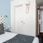 Chambre Familiale Supérieure avec un lit et une lampe murale à l’hôtel Astoria