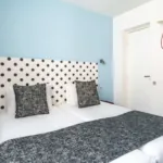 Lit de la Chambre Familiale Supérieure avec des pois noirs et blancs sur la tête de lit à l’hôtel Astoria