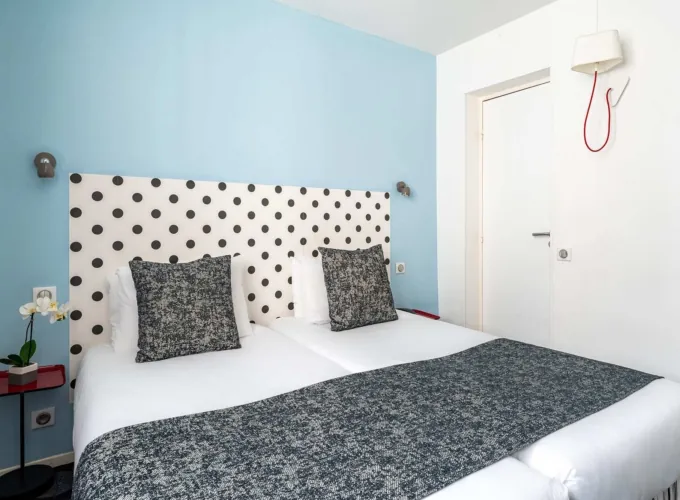 Lit de la Chambre Familiale Supérieure avec des pois noirs et blancs sur la tête de lit à l’hôtel Astoria