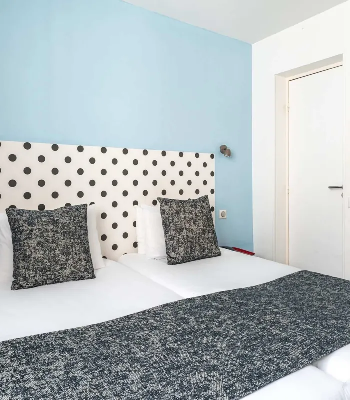 Lit de la Chambre Familiale Supérieure avec des pois noirs et blancs sur la tête de lit à l’hôtel Astoria