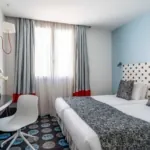 Chambre Familiale Supérieure avec deux lits et une tête de lit à pois à l’hôtel Astoria