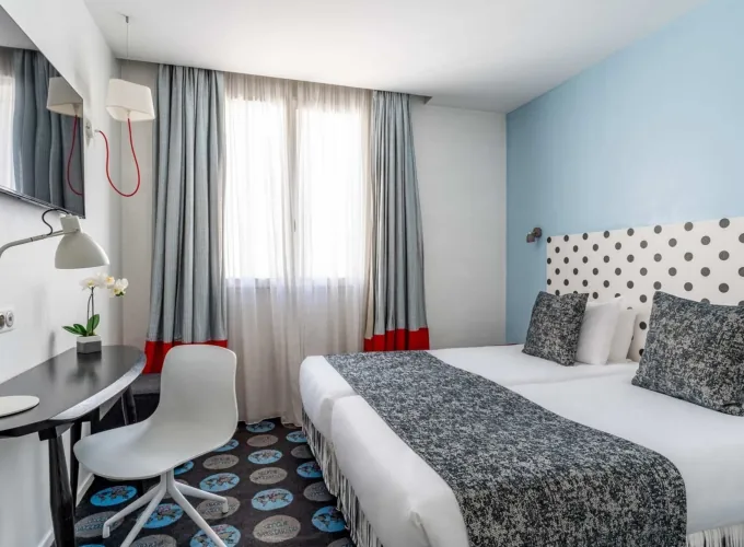 Chambre Familiale Supérieure avec deux lits et une tête de lit à pois à l’hôtel Astoria