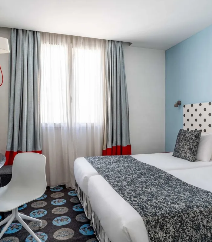 Chambre Familiale Supérieure avec deux lits et une tête de lit à pois à l’hôtel Astoria