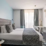 Chambre Privilège avec deux lits et un bureau à l’hôtel Astoria