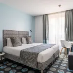 Chambre Privilège avec un lit et un bureau à l’hôtel Astoria