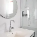 Salle de bain de la Chambre Privilège avec un lavabo et un miroir rond à l’hôtel Astoria