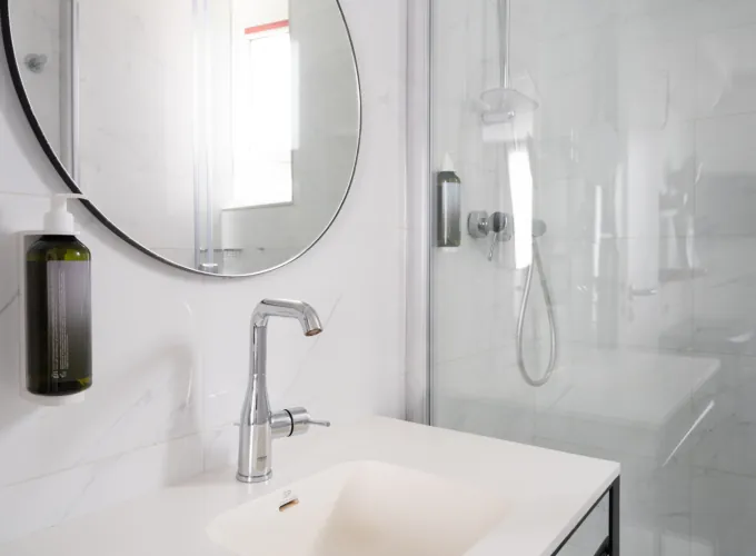 Salle de bain de la Chambre Privilège avec un lavabo et un miroir rond à l’hôtel Astoria
