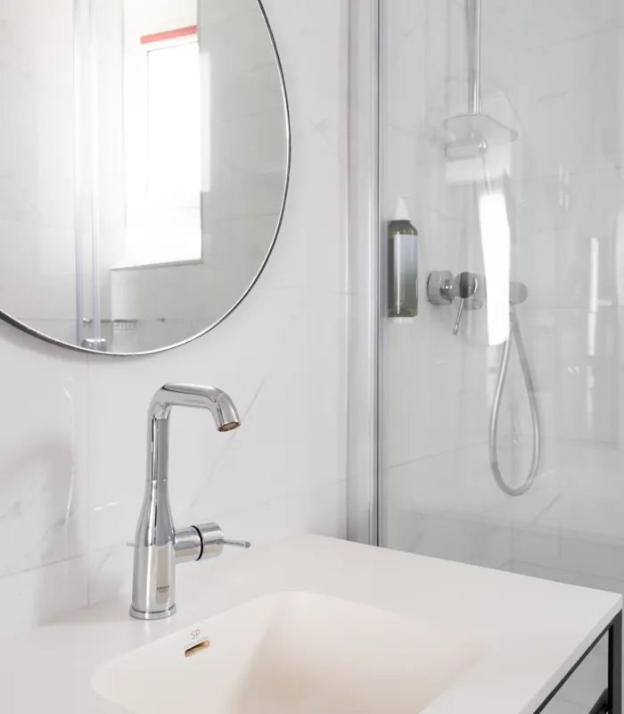 Salle de bain de la Chambre Privilège avec un lavabo et un miroir rond à l’hôtel Astoria