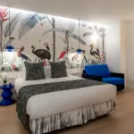 Chambre Quadruple avec un lit et une chaise bleue à l’hôtel Astoria