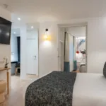 Chambre Quadruple avec un grand lit et une télévision à écran plat à l’hôtel Astoria
