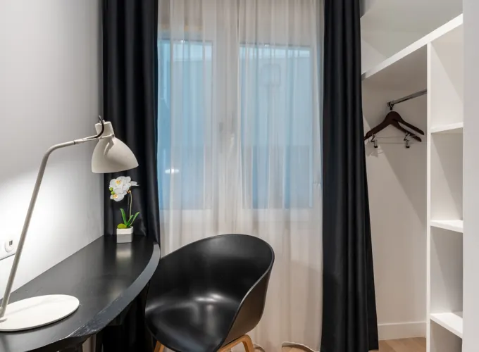 Chambre Quadruple avec une chaise noire à côté d’un bureau avec une lampe à l’hôtel Astoria