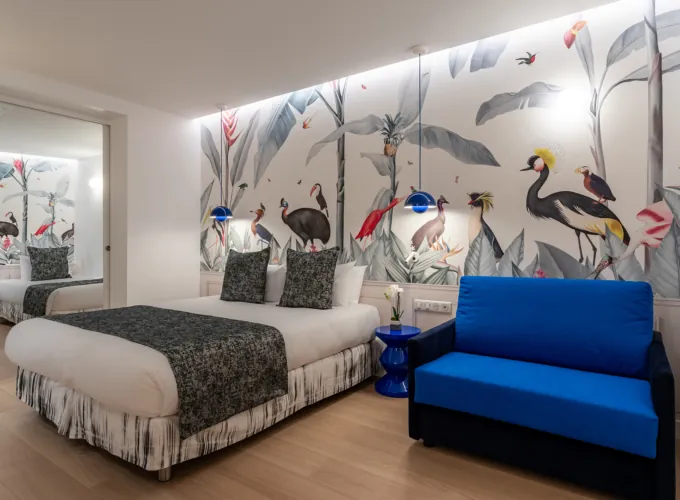 Chambre Quadruple avec un lit et une chaise avec des oiseaux sur le mur à l’hôtel Astoria