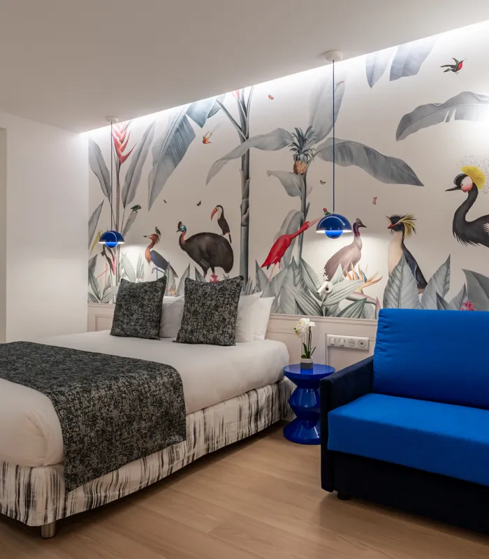 Chambre Quadruple avec un lit et une chaise avec des oiseaux sur le mur à l’hôtel Astoria