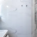 Salle de bain de la Chambre Quadruple avec des carreaux en marbre blanc et une douche à l’hôtel Astoria