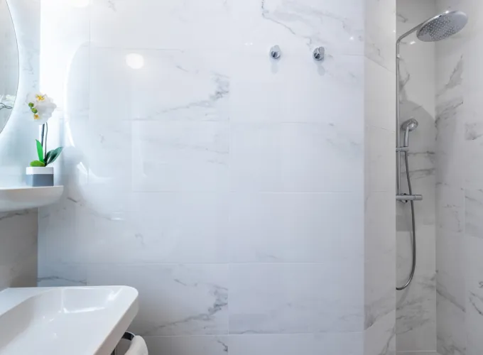Salle de bain de la Chambre Quadruple avec des carreaux en marbre blanc et une douche à l’hôtel Astoria