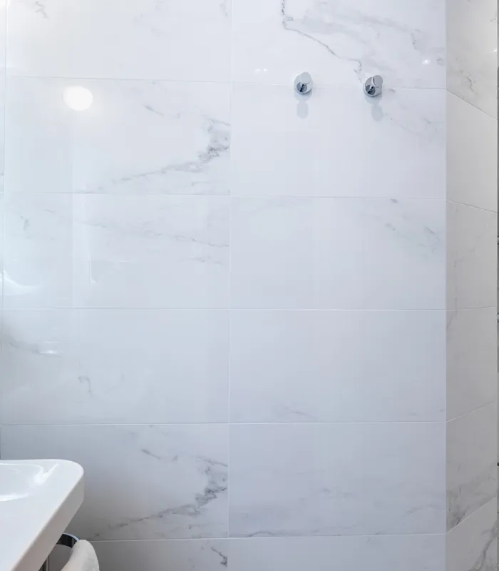 Salle de bain de la Chambre Quadruple avec des carreaux en marbre blanc et une douche à l’hôtel Astoria