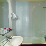 Salle de bain de la Chambre Triple avec un lavabo, un miroir et une baignoire à l’hôtel Astoria