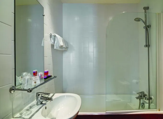 Salle de bain de la Chambre Triple avec un lavabo, un miroir et une baignoire à l’hôtel Astoria