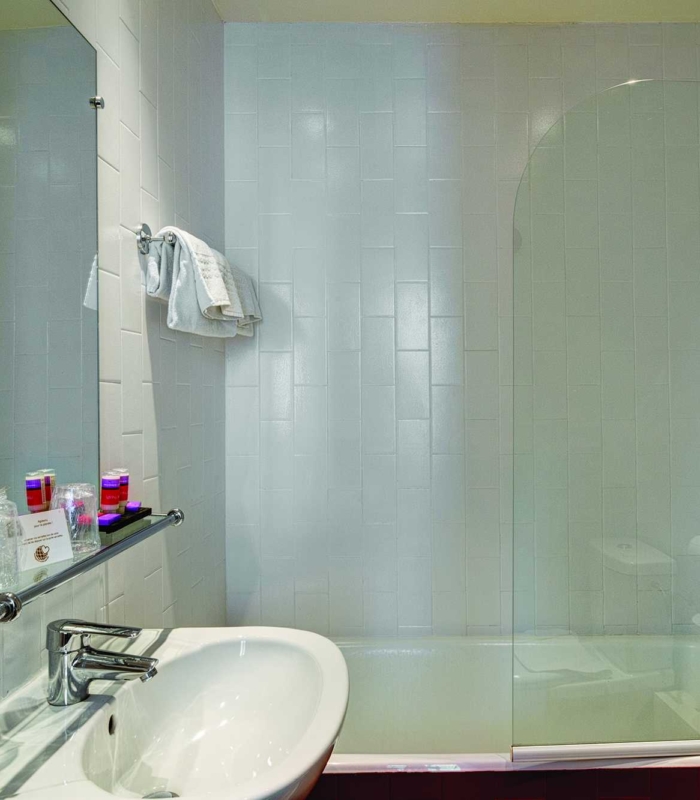 Salle de bain de la Chambre Triple avec un lavabo, un miroir et une baignoire à l’hôtel Astoria