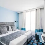 Chambre Twin avec deux lits et un bureau à l’hôtel Astoria
