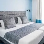 Chambre Twin avec deux lits et un mur bleu à l’hôtel Astoria