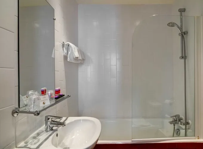 Salle de bain de la Chambre Twin avec un lavabo, un miroir et une baignoire à l’hôtel Astoria
