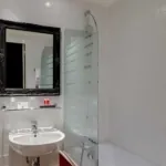 Salle de bain de la Chambre Twin Supérieure avec un lavabo, un miroir et une baignoire à l’hôtel Astoria