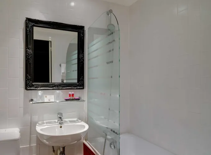 Salle de bain de la Chambre Twin Supérieure avec un lavabo, un miroir et une baignoire à l’hôtel Astoria