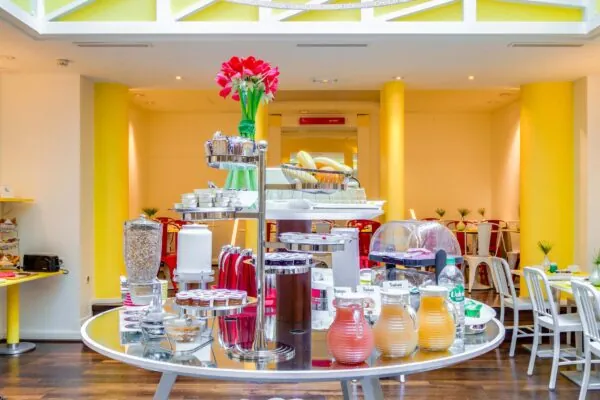 Salle de petit-déjeuner de l’hôtel Astoria à Paris avec buffet varié, ambiance chaleureuse et décor animé.