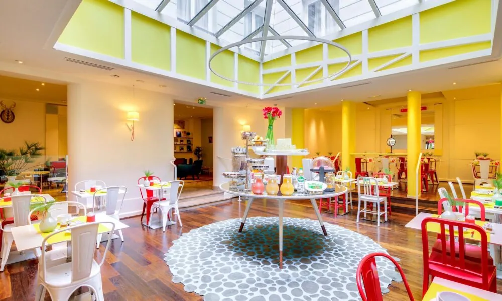 Salle de petit-déjeuner de l’hôtel Astoria à Paris avec buffet varié, ambiance chaleureuse et décor animé.