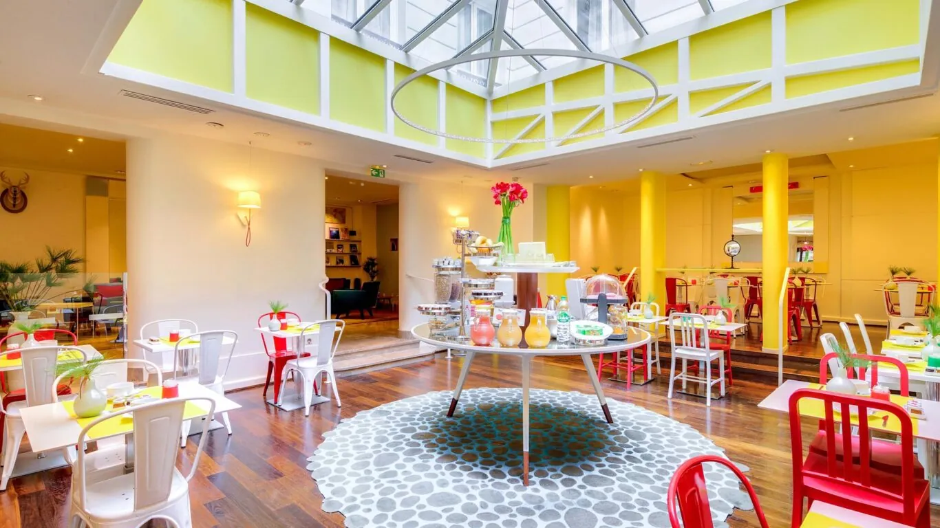 Salle de petit-déjeuner de l’hôtel Astoria à Paris avec buffet varié, ambiance chaleureuse et décor animé.