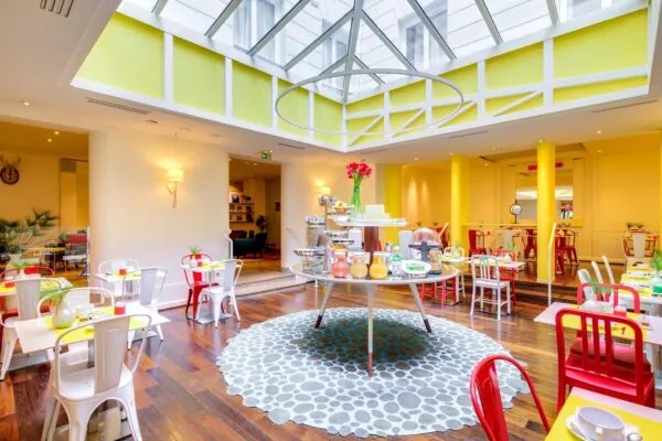 Salle de petit-déjeuner de l’hôtel Astoria à Paris avec buffet varié, ambiance chaleureuse et décor animé.