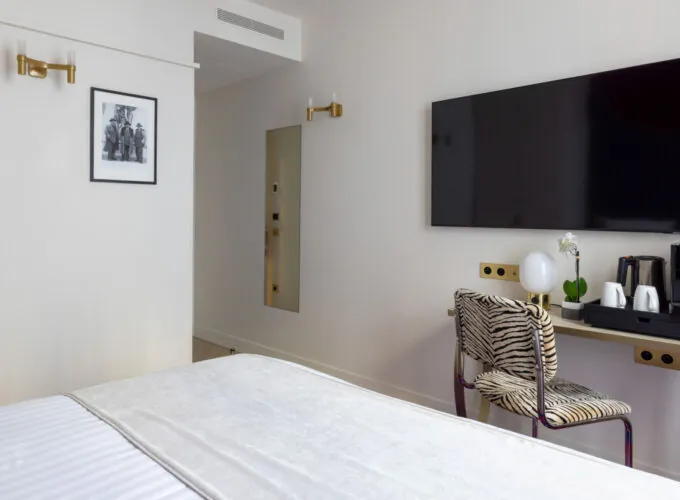 Chambre Double Standard Bouglione avec une chaise à motif zèbre et une télévision à écran plat à l’hôtel Astra Opéra